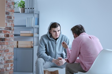 A correctional counselor works with a juvenile patient in a counseling session.