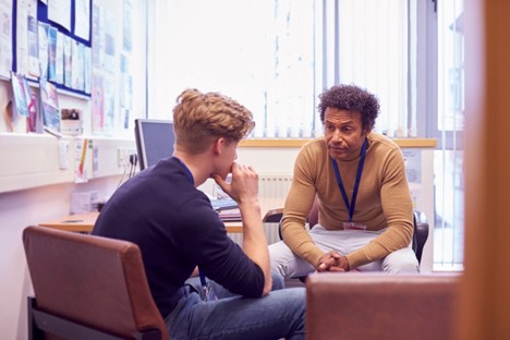 A school counselor meets with a student in his office.