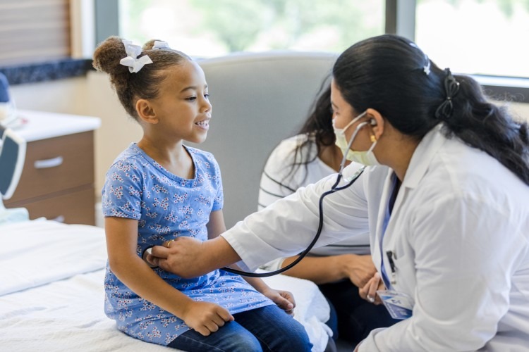A family nurse practitioner uses a stethoscope on a child patient.