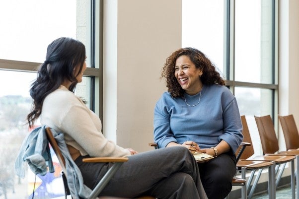 A counselor and a field placement student sitting in chairs and laughing. 