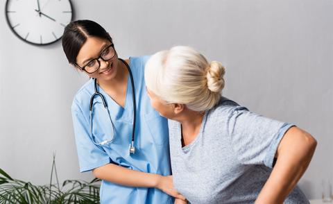 nurse with glasses assisting a gray-haired patient