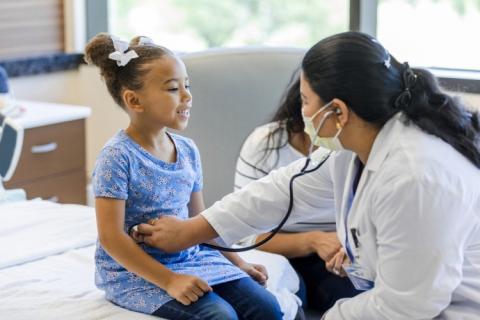 A family nurse practitioner uses a stethoscope on a child patient.