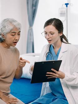 A young nurse speaking with an older patient about paperwork